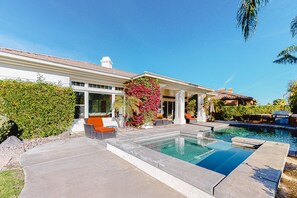 Ein modernes Haus mit Swimmingpool, Sitzgelegenheiten im Freien und üppiger Bepflanzung.