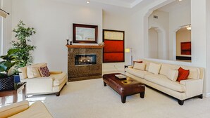Ein geräumiges Wohnzimmer mit Kamin, einer großen Couch, einem Couchtisch und einer Zimmerpflanze.