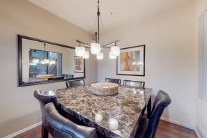 Ein Esszimmer mit einem Marmortisch, Ledersesseln, einer Chandelierleuchtre und gerahmten Kunstwerken an den Wänden.