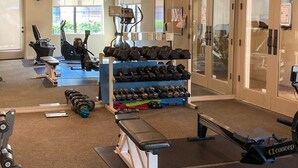 Une salle de sport équipée de machines d’exercice, d’haltères et d’un tapis de course.