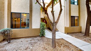 Un bâtiment à la façade beige, un arbre au premier plan et un escalier menant à un étage supérieur.