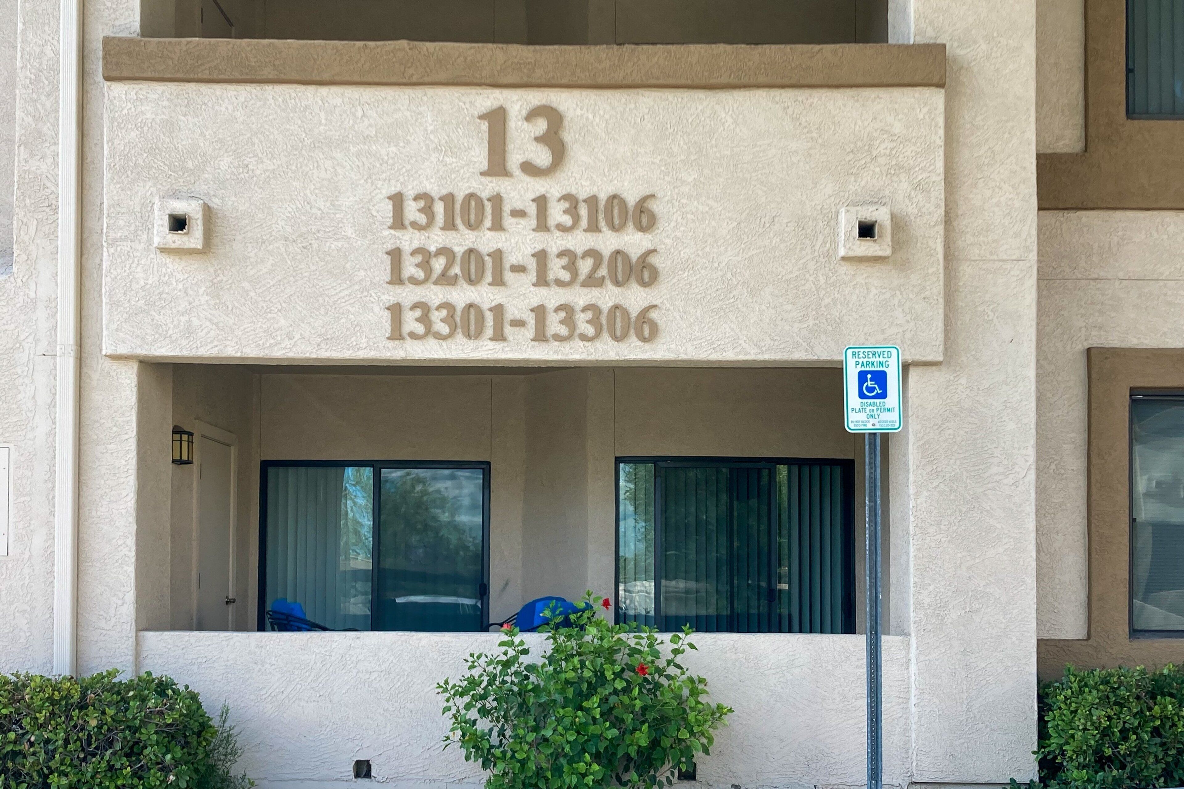 A building with a numbered address sign and a reserved parking sign.