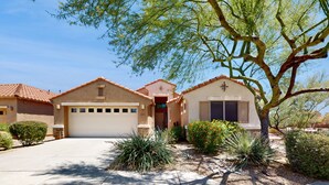 A two-story house with a garage, a small porch, and a landscaped front yard with cacti and shrubs. - Pristine Desert Ridge home with a pool & backyard oasis - dog-friendly (Phoenix)