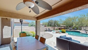 An outdoor patio with a table and chairs, a ceiling fan, and a view of a swimming pool and backyard. - Pristine Desert Ridge home with a pool & backyard oasis - dog-friendly (Phoenix)