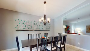 A dining area with a long table, six chairs, a chandelier, and a wall art piece above the table. - Pristine Desert Ridge home with a pool & backyard oasis - dog-friendly (Phoenix)