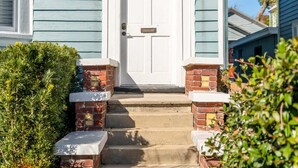 A house with a white front door, number 140, and a small porch with steps leading up to it. - Historic, Spacious Loft w. Kitchen + Living Room (Charleston)