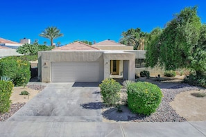 A single-story house with a garage, surrounded by landscaped gardens and palm trees. - Desert Bliss with Mountain Views & a Sparkling Private Pool. (Palm Desert)