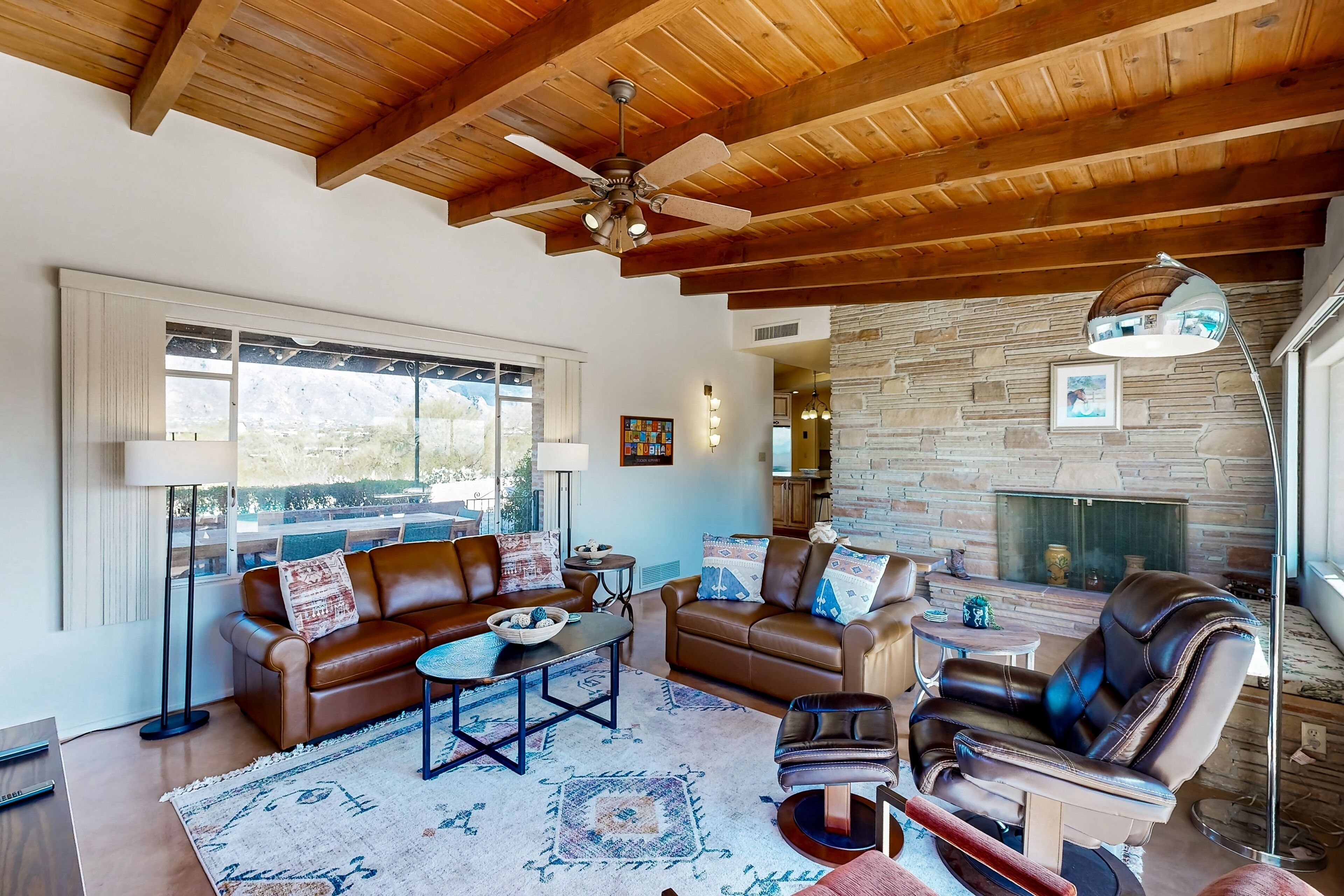 A spacious living room with leather sofas, a coffee table, and a fireplace.
