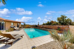 A swimming pool with lounge chairs, a brick wall, and a clear sky. - Dog-friendly oasis with yard, amazing pool, furnished patio, & washer/dryer (Tucson)