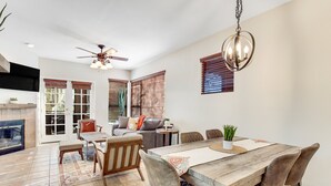 A spacious living area with a dining table, comfortable seating, a fireplace, and a ceiling fan. - Radiant retreat with pool and hot tub access, sunroom, washer/dryer, gym, & AC (Tucson)