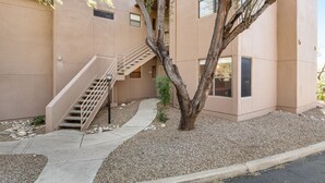 A building with a beige exterior, a staircase leading to an upper level, and a tree in the foreground. - Radiant retreat with pool and hot tub access, sunroom, washer/dryer, gym, & AC (Tucson)