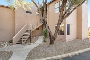 A building with a beige exterior, a staircase leading to an upper level, and a tree in the foreground. - Radiant retreat with pool and hot tub access, sunroom, washer/dryer, gym, & AC (Tucson)