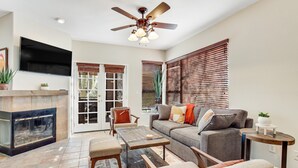 A living room with a fireplace, a sofa, a coffee table, and a television mounted on the wall. - Radiant retreat with pool and hot tub access, sunroom, washer/dryer, gym, & AC (Tucson)