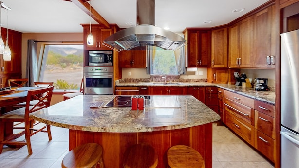 Una cucina moderna con mobili in legno, un'isola centrale, elettrodomestici in acciaio inossidabile e un'ampia finestra con vista sull'esterno.