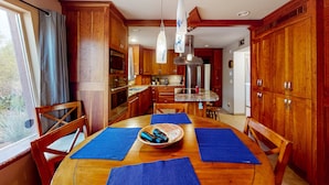 Una cucina con mobili in legno, un tavolo da pranzo con sottopiatti blu e lampade a sospensione.