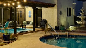 Un'area piscina con una pergola, sedie a sdraio e una fontana.