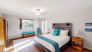 Una camera da letto con un letto grande, una testiera in legno, una panca, un comodino e vista sull'esterno.