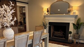 Un comedor con una mesa y sillas de madera, una chimenea y un espejo decorativo encima.
