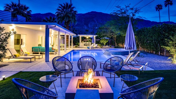 Une terrasse extérieure moderne, dotée d’un foyer, de chaises longues et d’une piscine.