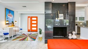 Un salon moderne avec un canapé orange vif, un tapis coloré et un design minimaliste.