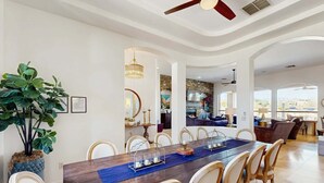 Un comedor con mesa de madera, sillas y una planta grande.