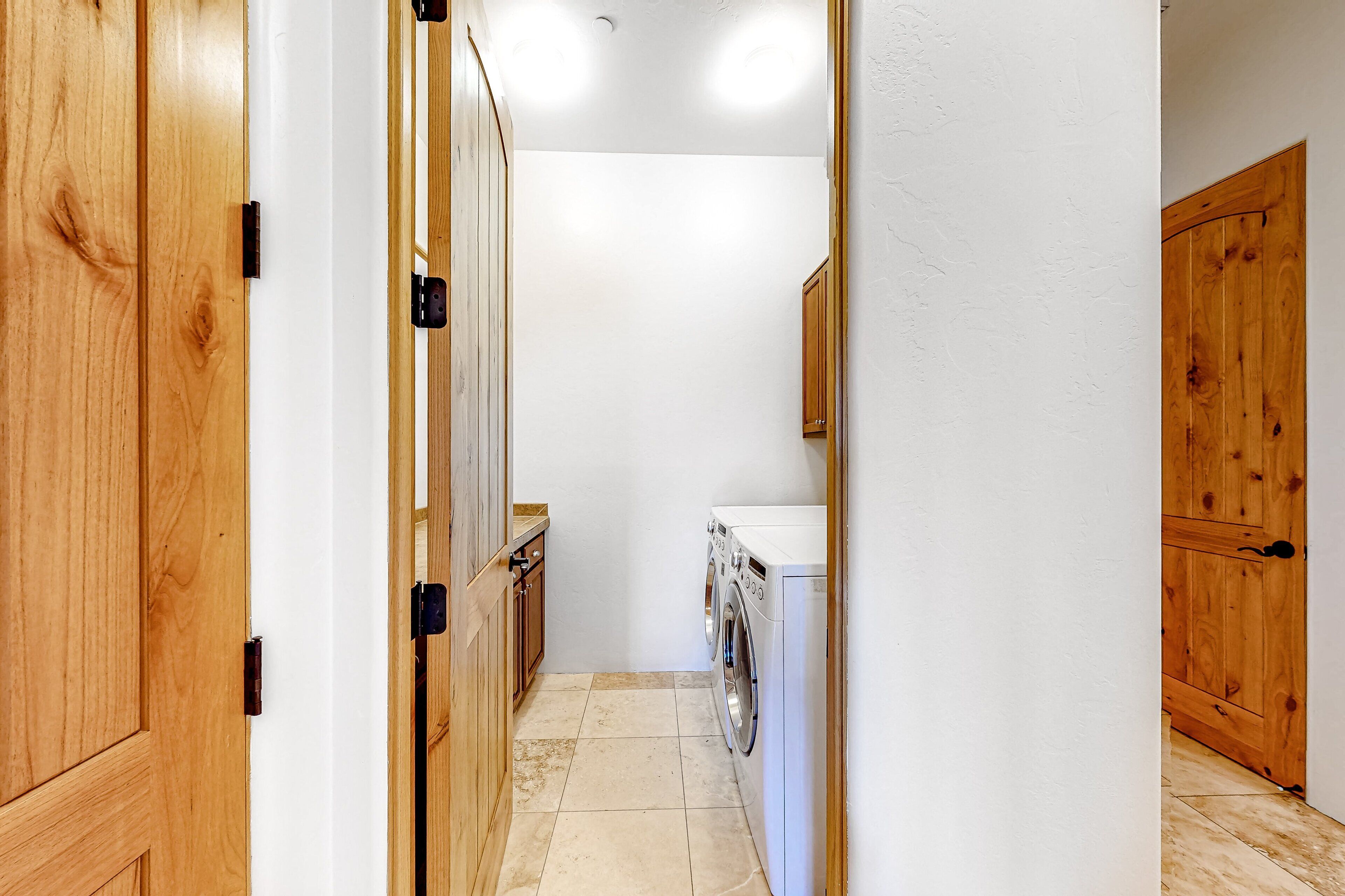 Un couloir étroit avec des portes en bois, un lave-linge et un plan de travail.