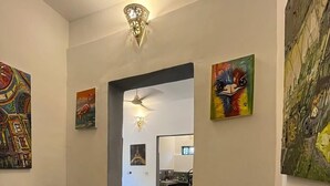 A hallway with a dining area, featuring a ceiling fan, decorative wall sconces, and artwork.