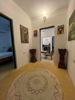 A hallway with a patterned rug, two decorative vases, and artwork on the walls.