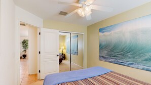 A bedroom with a bed, a ceiling fan, a painting of a wave, and a door leading to another room. - Desert oasis with an enclosed yard, firepit, washer/dryer, and central AC (Gilbert)