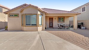 A single-story house with a tiled roof, a covered patio area with a table and chairs, and a barbecue grill. - Desert oasis with an enclosed yard, firepit, washer/dryer, and central AC (Gilbert)