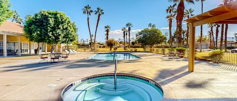 A swimming pool with a circular design, surrounded by palm trees and a covered seating area.
