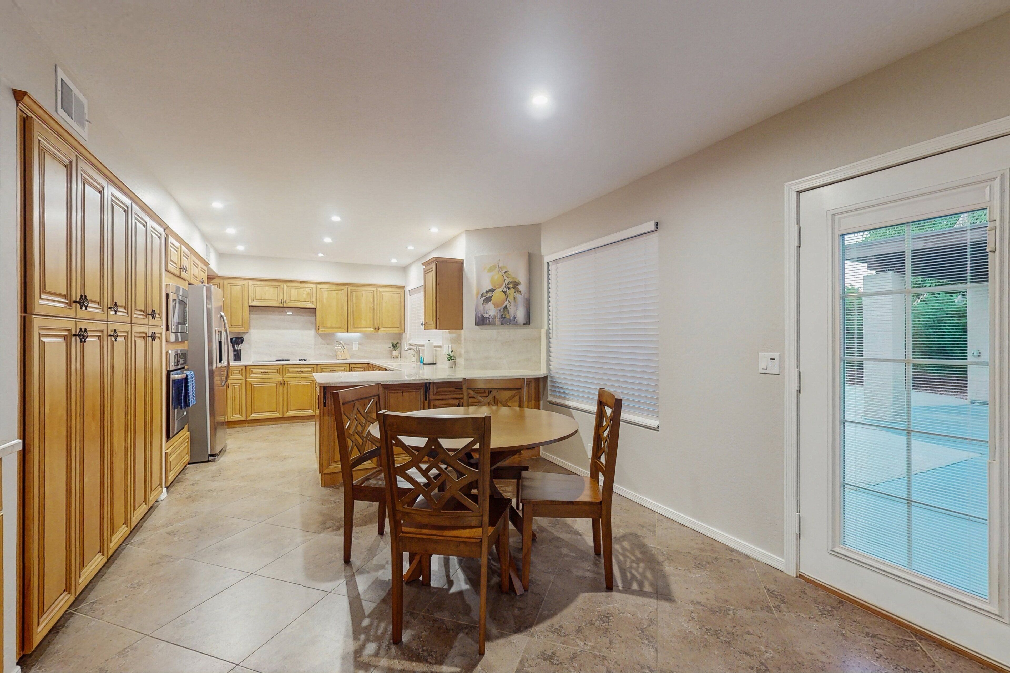 A kitchen with wooden cabinets, a dining table with chairs, and a sliding glass door.