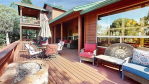 Une terrasse en bois avec des meubles d’extérieur, un foyer et une vue sur un immeuble doté d’un balcon.