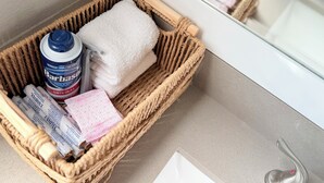 A wicker basket containing a Barbasol shaving cream can, a white towel, and a pink and white patterned cloth on a bathroom counter. - Pretty in pink studio/Montrose HTX/Free parking + WIFI (Houston)