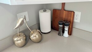A kitchen counter with a white cabinet, a roll of paper towels, two salt and pepper shakers, and a decorative golden apple. - Pretty in pink studio/Montrose HTX/Free parking + WIFI (Houston)