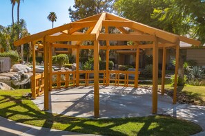 Un belvédère en bois offrant une vue dégagée sur le jardin et l’espace piscine environnants.