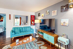 Ein modernes Wohnzimmer mit einem blaugrünen Sofa, einem Holztisch und einem Vintage-Radio.