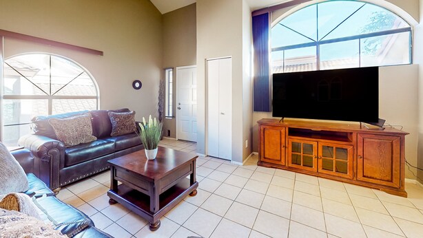 A living room with a leather sofa, a coffee table, and a TV on a wooden cabinet. - Gated-entry condo with central location, central AC, & private W/D (Phoenix)