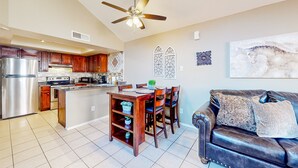 A spacious kitchen with wooden cabinets, a stainless steel refrigerator, and a dining area with a table and chairs. - Gated-entry condo with central location, central AC, & private W/D (Phoenix)