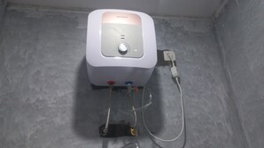 A white portable heater with a control panel and a hose connected to a metal stand. - OYO 95179 Namira Guest House Syariah (Kembaran)