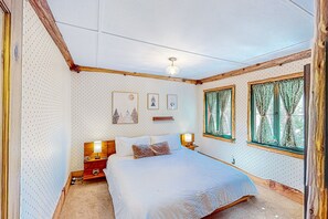 Una camera da letto con un letto, due comodini, una lampada a parete e una finestra con tende.