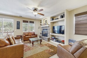 A living room with a fireplace, leather sofas, a coffee table, and a TV.