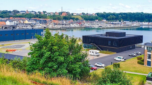 A marina with boats, a modern building, and a view of a town with houses and greenery. - Cozy home in Lemvig with WiFi (Lemvig)