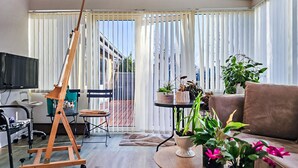 A living room with a wooden easel, a television, a sofa, and various potted plants. - Cozy home in Lemvig with WiFi (Lemvig)