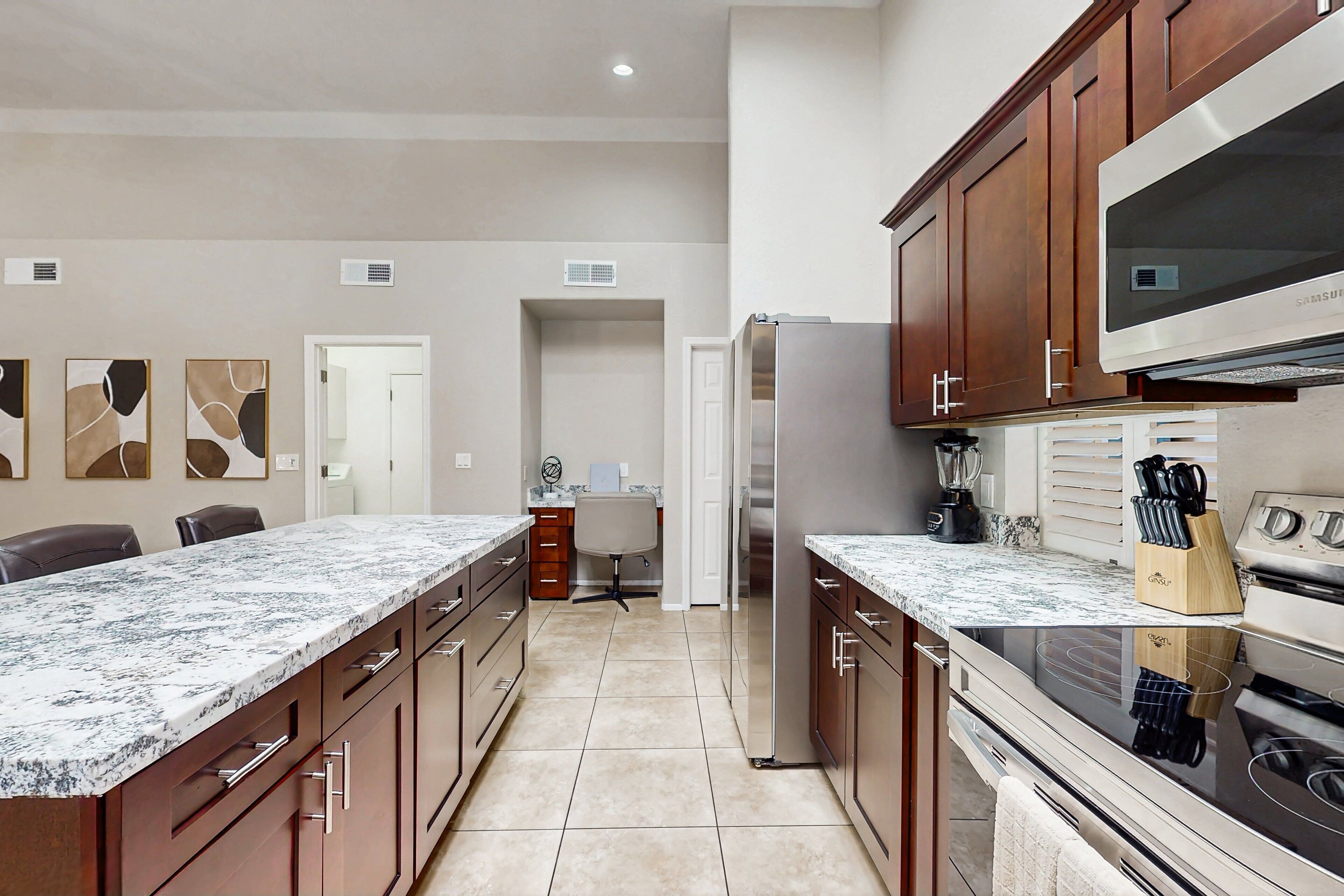 A kitchen with a granite countertop, stainless steel appliances, wooden cabinets, and a microwave.