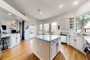 A modern kitchen with wooden flooring, white cabinetry, and a large island. - Expansive mountain views!  Spacious retreat near Catalina State Park! (Oro Valley)