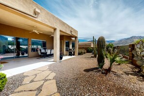 Una casa moderna con patio, ventanas amplias y vistas a montañas.