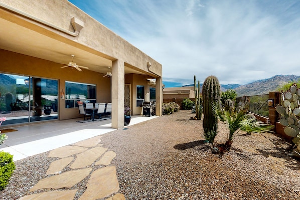A modern house with a patio, outdoor furniture, and a desert garden with cacti.