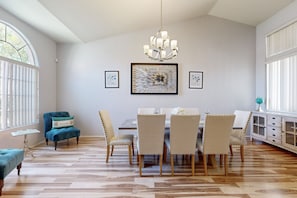 Ein Essbereich mit einer Chandelüster, einem Tisch mit Stühlen und Kunstwerken an der Wand.