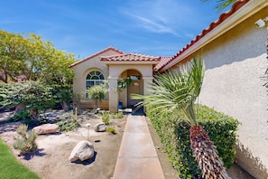A house with a tiled roof, a paved driveway, and a garden with various plants and a palm tree. - Chic Cathedral City Home with Private Pool & Spa | Minutes to Palm Springs (Cathedral City)